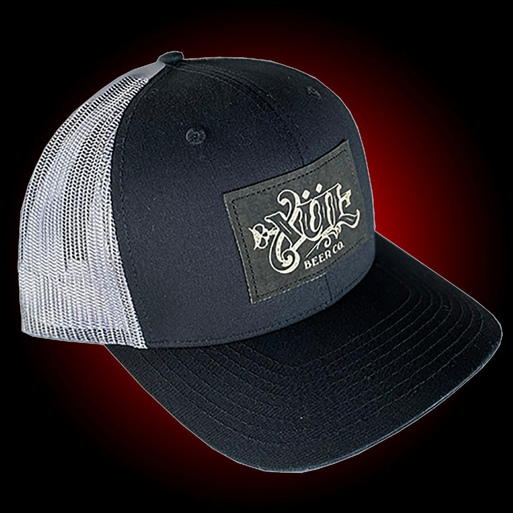 Black mesh trucker hat with our full logo on a black leather patch.
