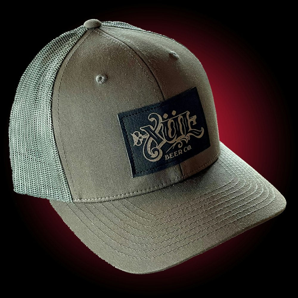 Dark green mesh trucker hat with our full logo on a black leather patch.